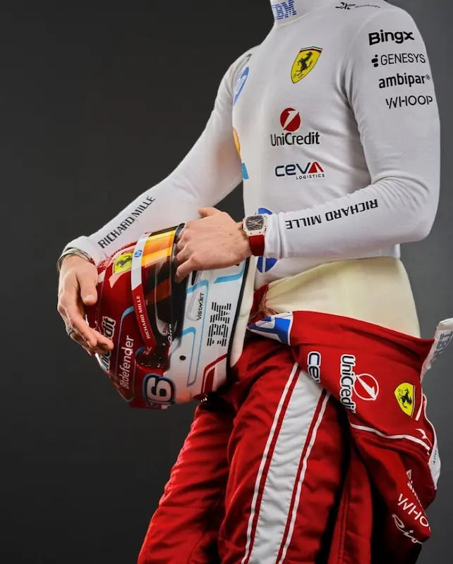 Person wearing a racing suit with various sponsor logos, holding a helmet.