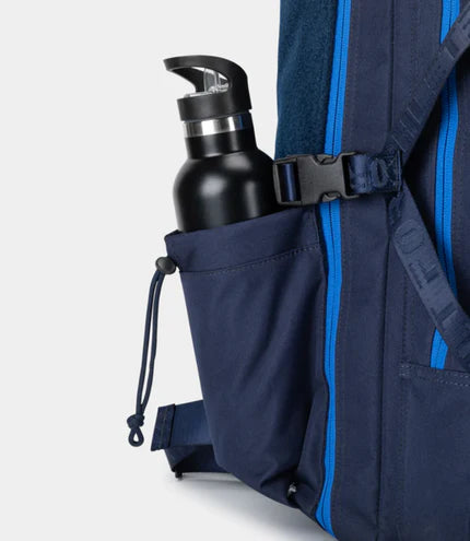 Navy backpack with a water bottle in a side pocket on a light gray background
