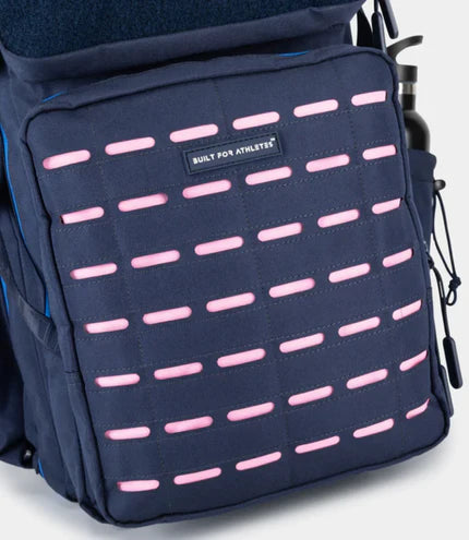 Navy backpack with pink accents and a visible brand label on a light gray background