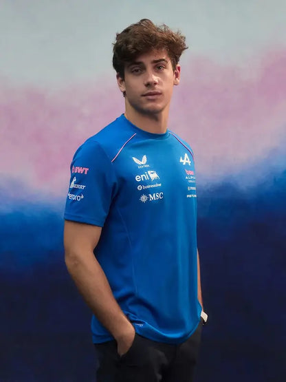 Person wearing a blue sports jersey with various logos against a gradient background