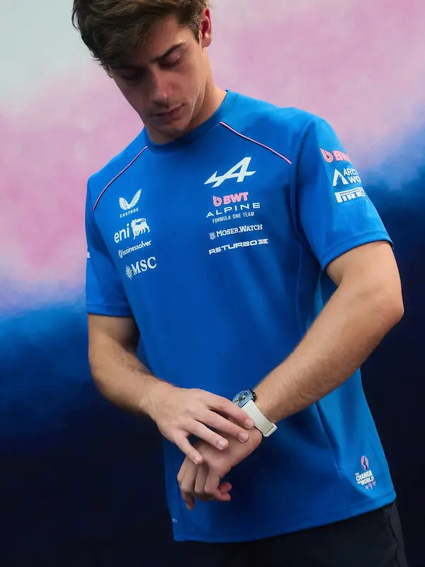 Person wearing a blue racing shirt with various sponsor logos against a gradient background