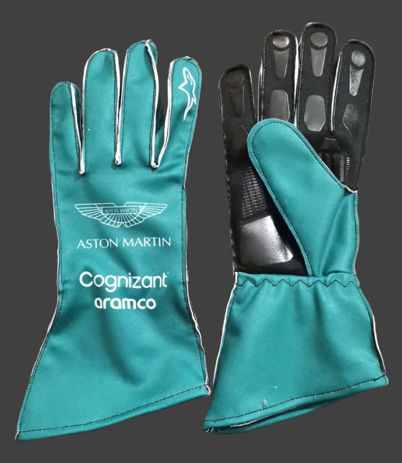 Teal racing gloves with Aston Martin and Cognizant Aramco branding on a gray background