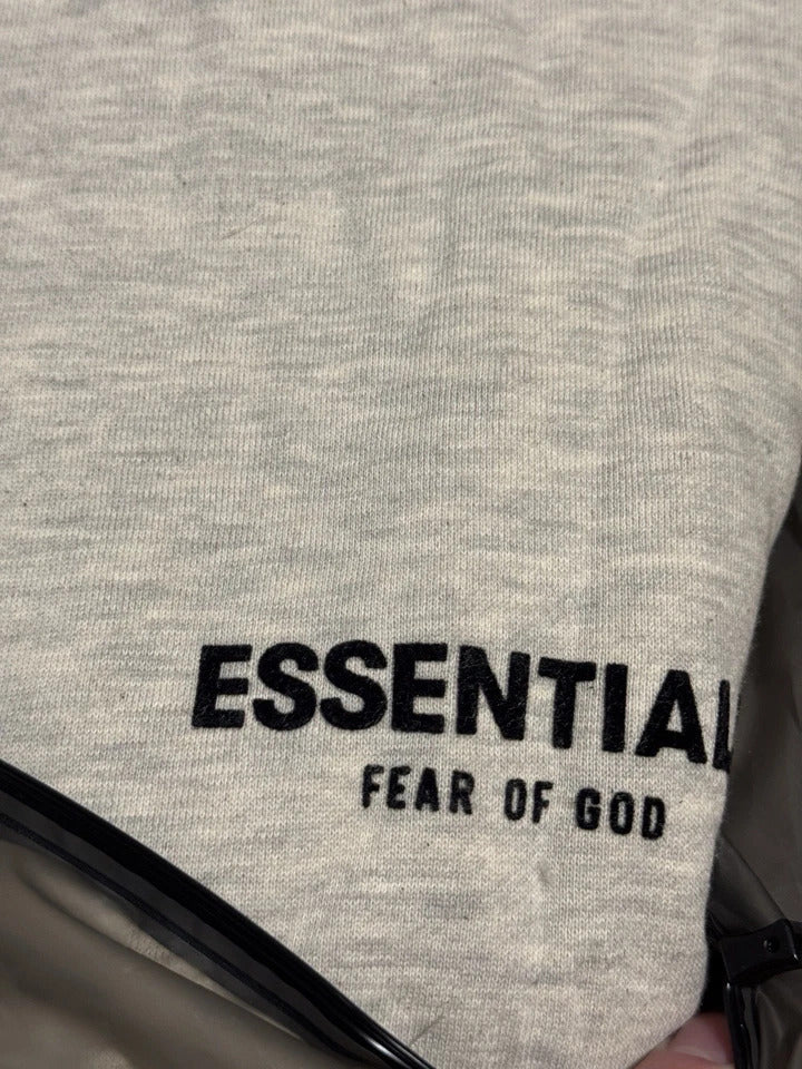 Gray sweatshirt with 'ESSENTIALS' and 'FEAR OF GOD' text on a plain background