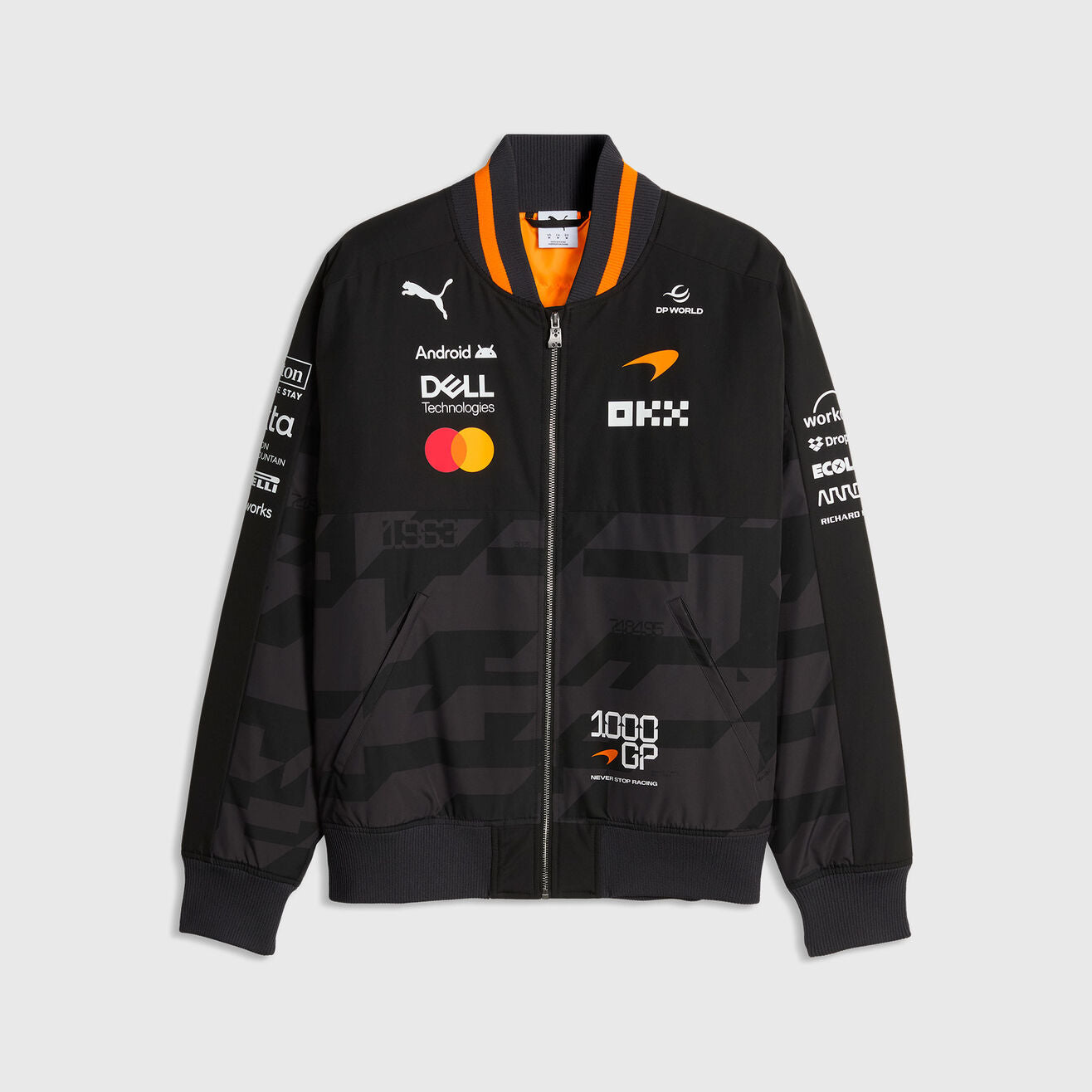 Front view of the black and gray McLaren inspired 1000th GP unisex bomber jacket with multi-sponsor logos, orange striped collar, and 1000 GP badge by TassFit Performance.