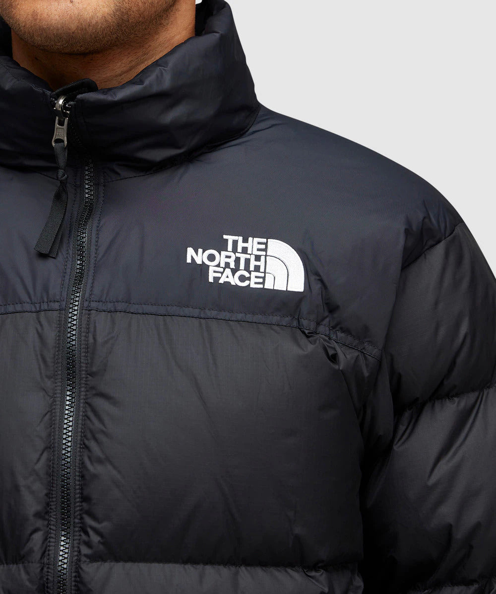 Black puffer jacket with The North Face logo on a gray background