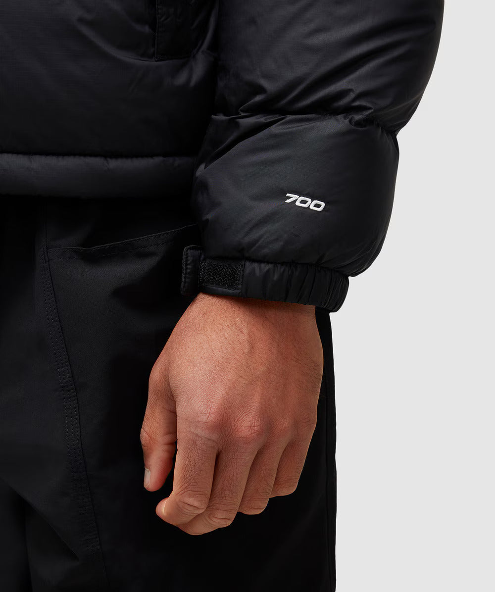 Close-up of a person wearing a black jacket with '700' branding on the sleeve against a white background