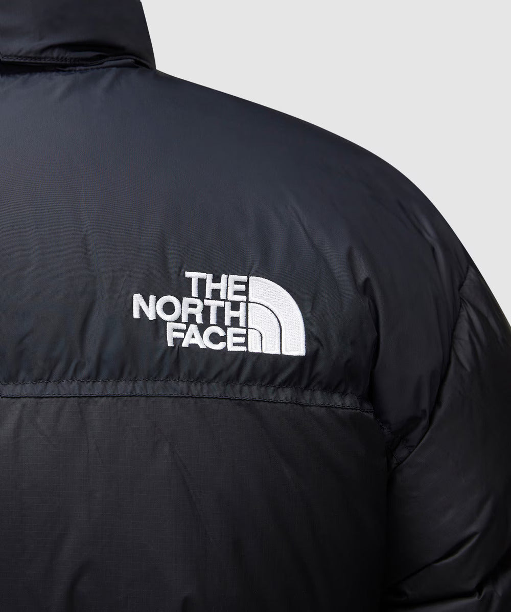 Black jacket with The North Face logo on a light gray background