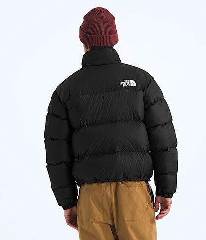 Person wearing a black puffer jacket with The North Face logo on a white background