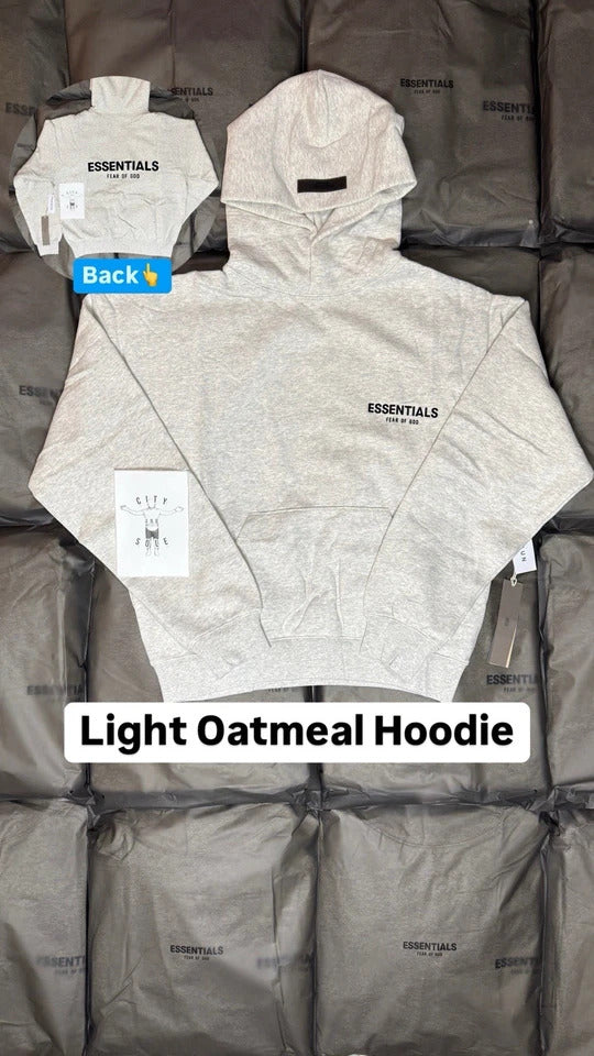 Light oatmeal hoodie displayed on a gray surface with 'ESSENTIALS' branding.